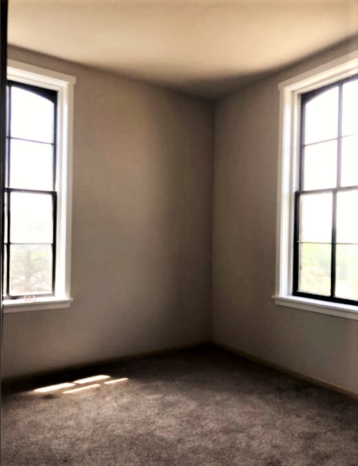 an empty room with two windows in it