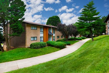 exterior view of Oaks at Park South apartments with green grass, trees and walking path between buildings