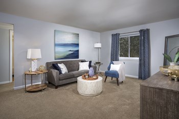 living room at Oaks at Park South apartments in Oxon Hill MD with gray couch, blue chair, coffee table, end table with lamp and credenza - Photo Gallery 3