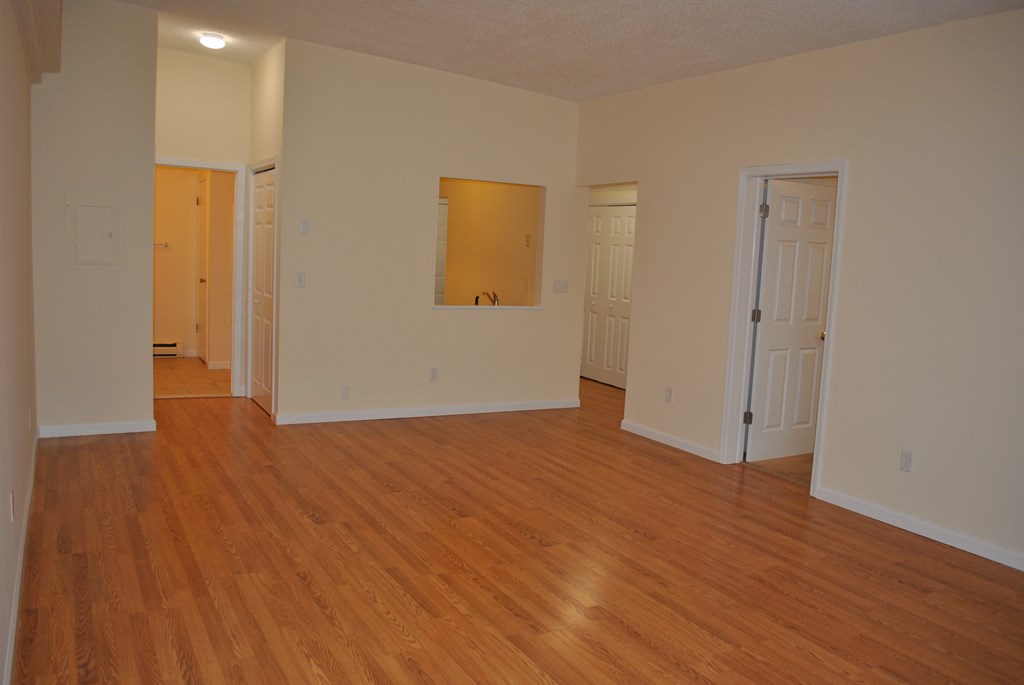 an empty living room with wood flooring and white walls