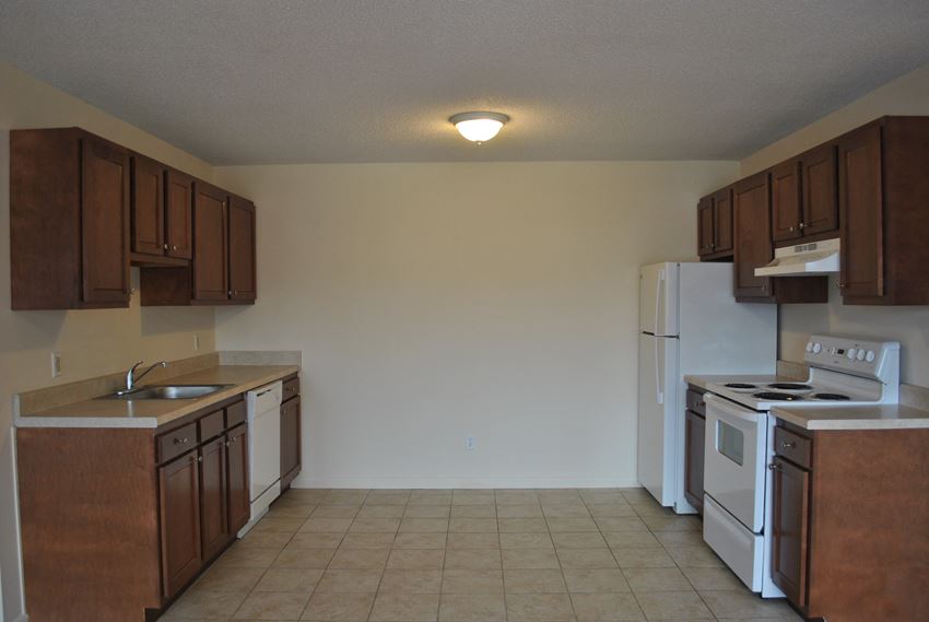 an empty kitchen with white appliances and wooden cabinets