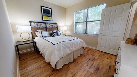 a bedroom with hardwood floors and a large window