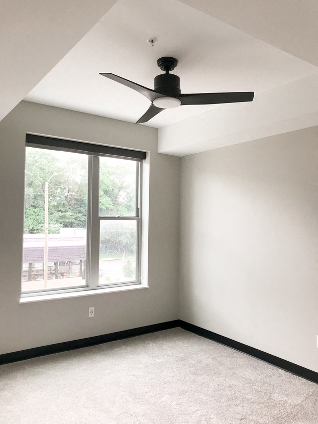 an empty room with a ceiling fan and a window