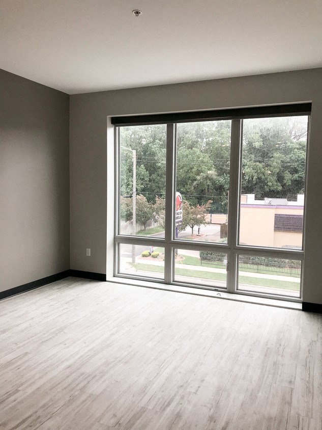 an empty living room with a large window and wooden floors