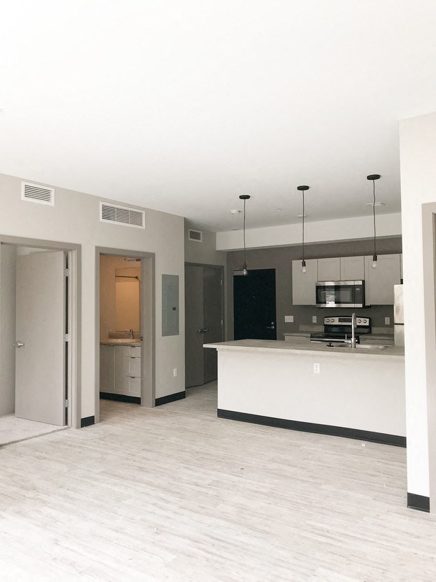 an empty kitchen and living room with a white counter top