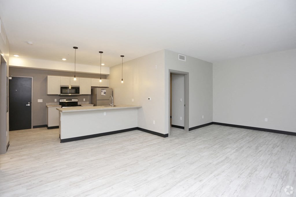 the living room and kitchen of an empty apartment with white floors and white walls