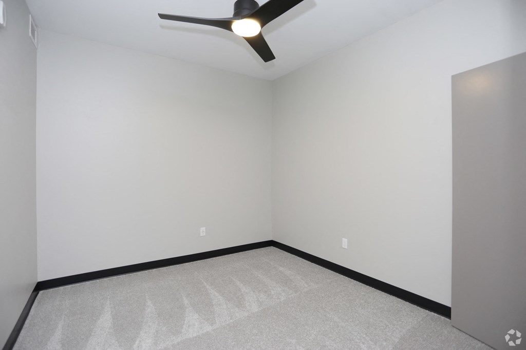 an empty room with a ceiling fan and white walls