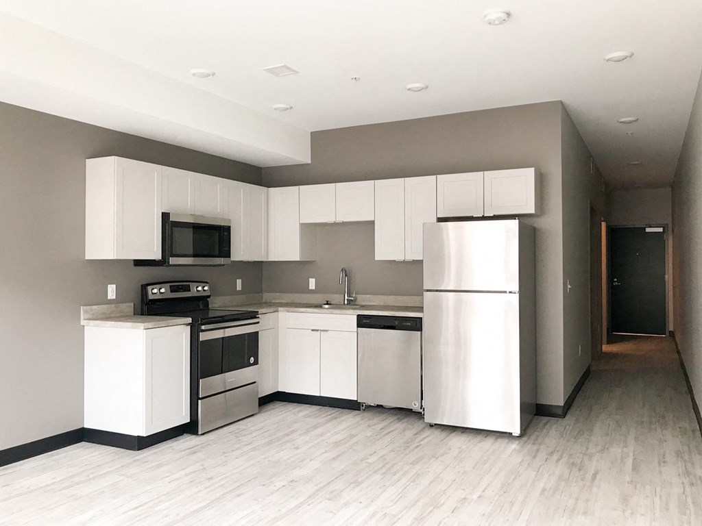 an empty kitchen with white cabinets and stainless steel appliances