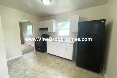 a kitchen with white cabinets and a black refrigerator