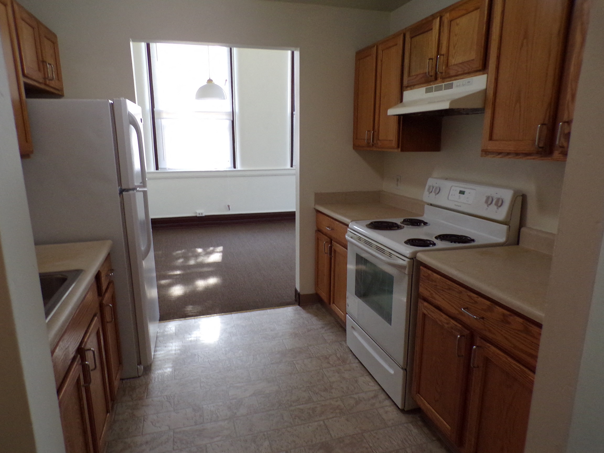 an empty kitchen with white appliances and wooden cabinets