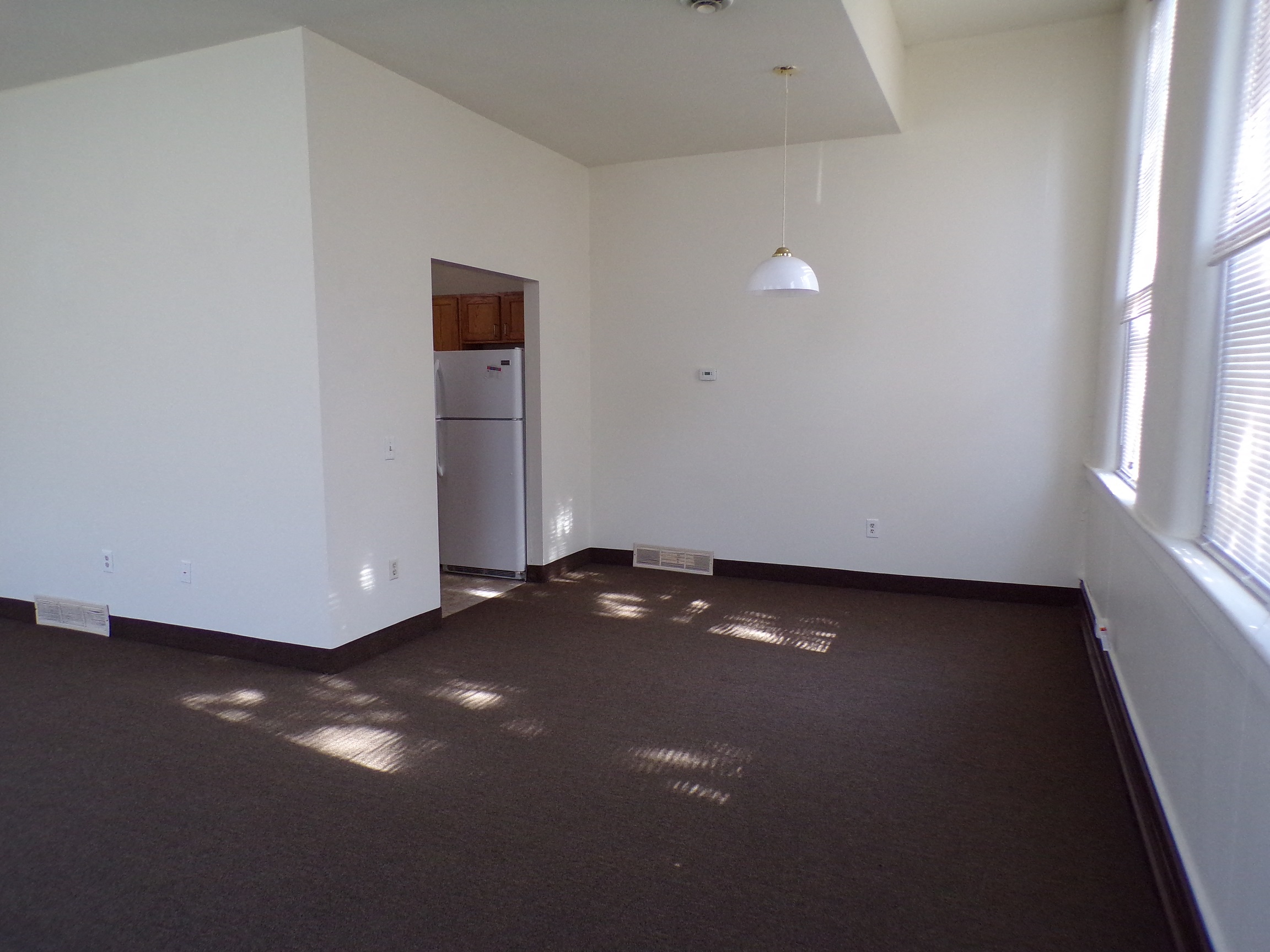 an empty living room with white walls and a large window