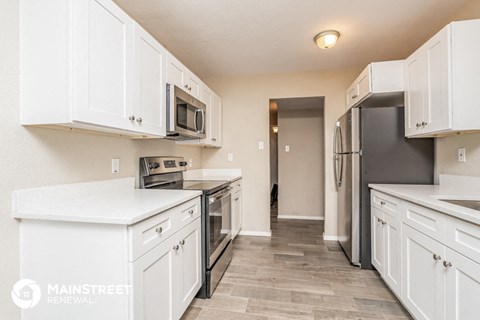 a white kitchen with stainless steel appliances and white cabinets