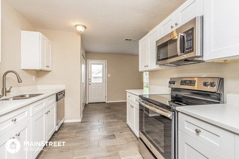 a kitchen with white cabinets and black appliances and stainless steel appliances