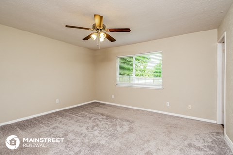 the spacious living room with carpeting and a ceiling fan