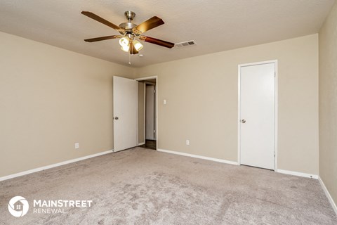 the spacious living room with carpet and ceiling fan