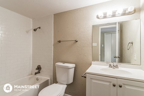 a bathroom with a toilet sink and mirror and a tub