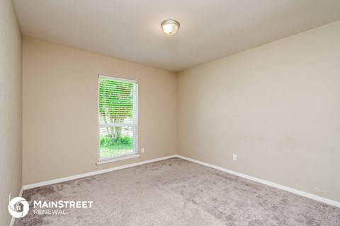 the spacious living room with carpeting and a window