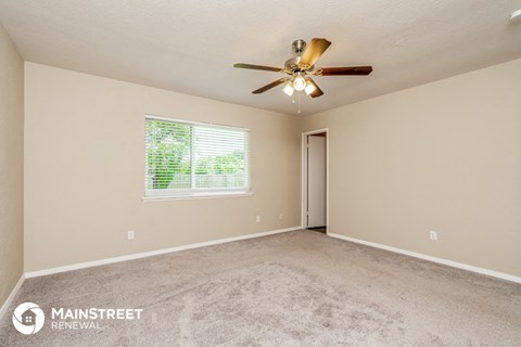 the spacious living room with carpeting and a ceiling fan