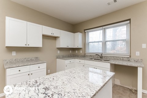 a white kitchen with granite counter tops and white cabinets