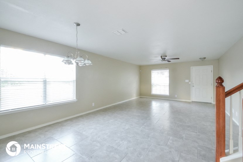 an empty living room with white tile flooring and a large window