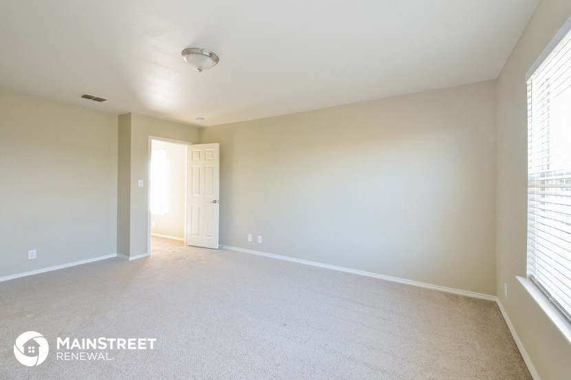 a white carpeted living room with a white door and window