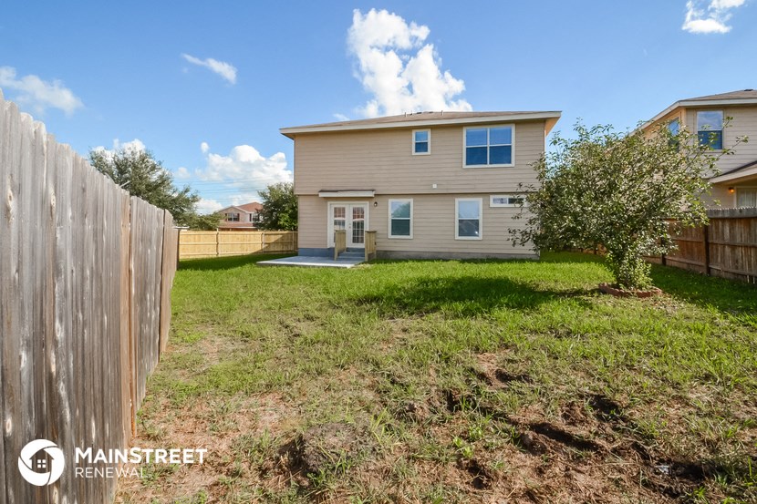 a backyard with a house and a wooden fence