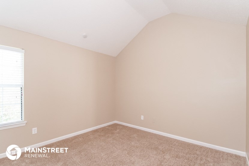 the upstairs bedroom with carpet and a window
