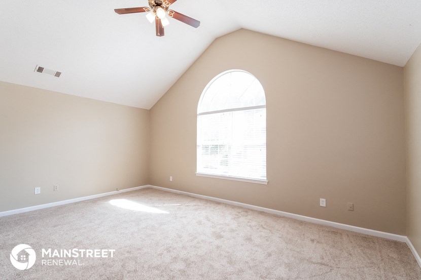 the master bedroom has a large window and carpeted flooring