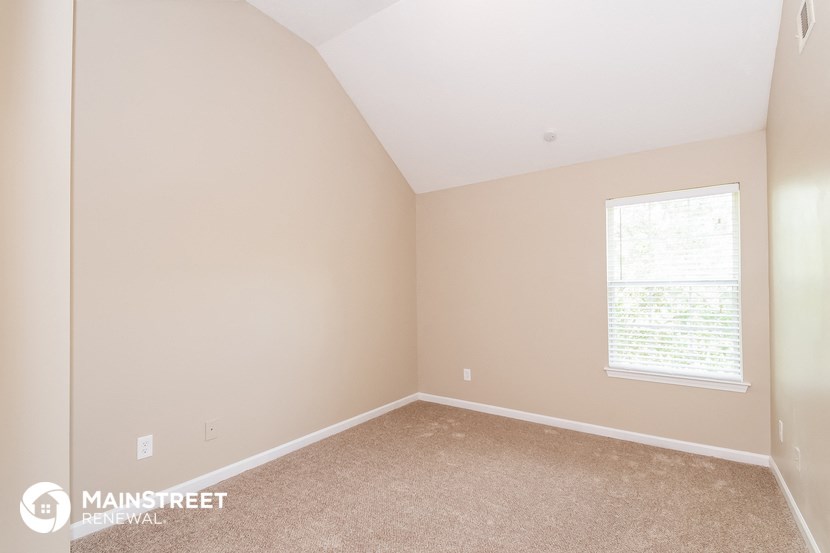 the bedroom of a home with beige carpet and a window