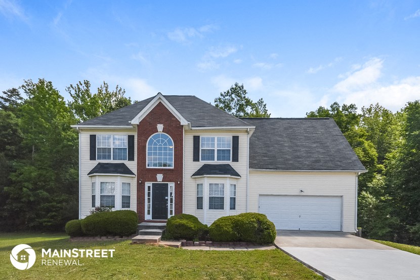 a white house with a black roof and white garage doors