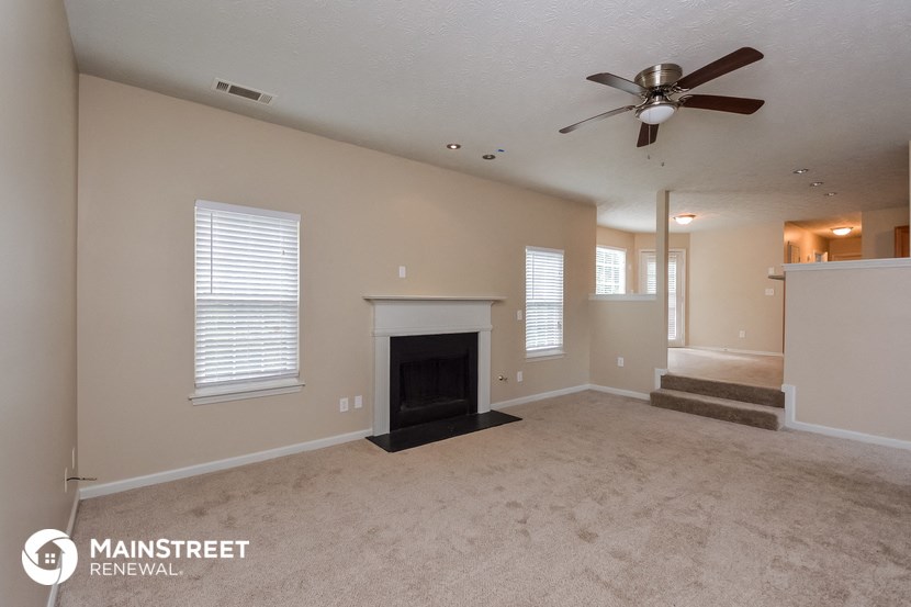 an empty living room with a fireplace and a ceiling fan