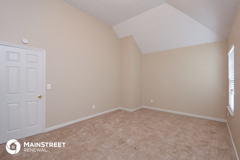 a bedroom with a white door and beige carpet