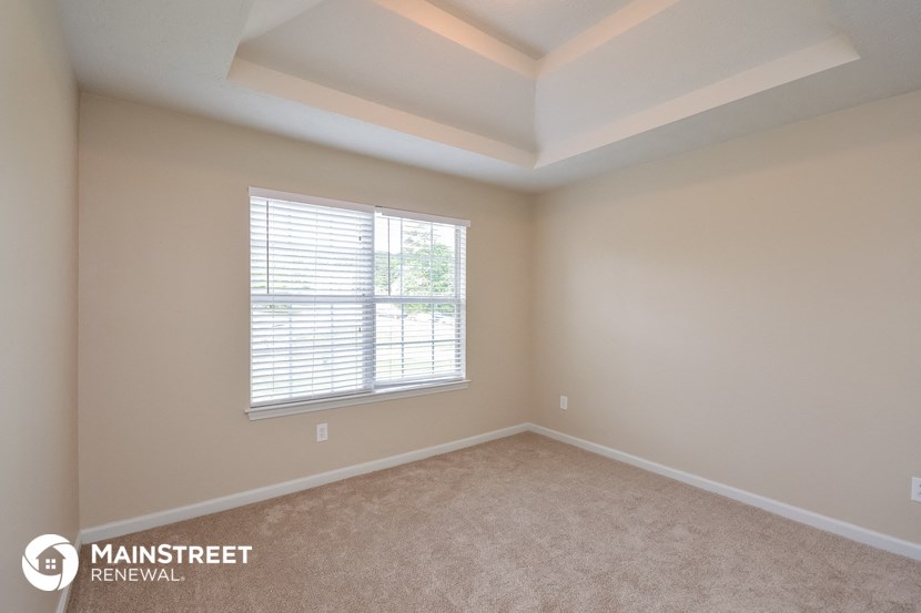 a bedroom with a large window and beige carpet