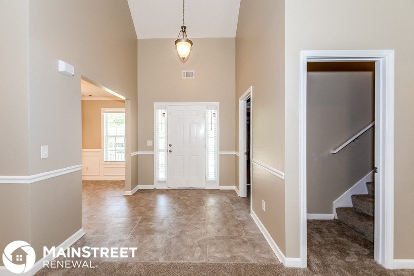 an empty living room with a staircase and a white door