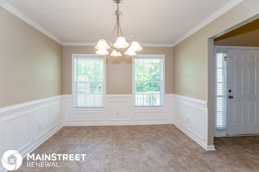 an empty dining room with white walls and a chandelier