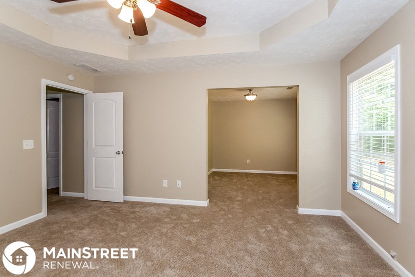 an empty living room with a ceiling fan and a window