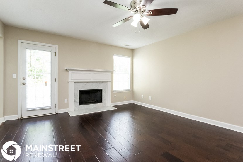 an empty living room with a fireplace and a ceiling fan