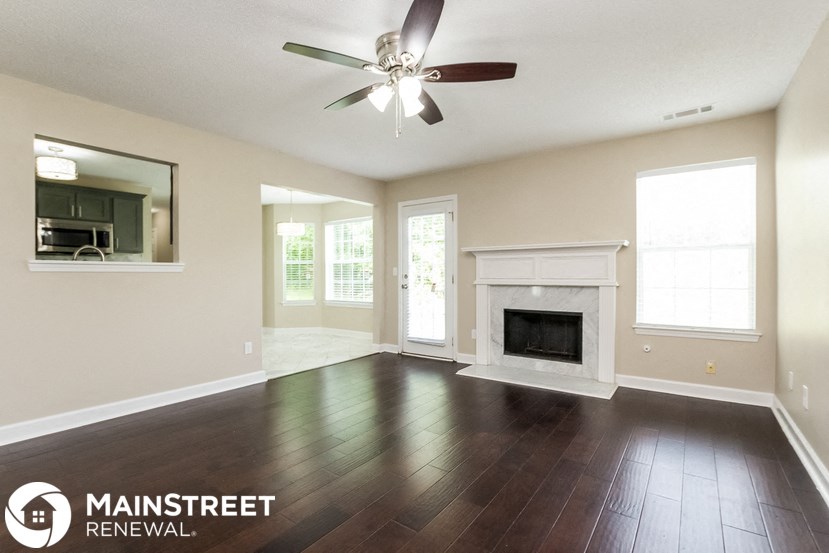 an empty living room with a ceiling fan and a fireplace