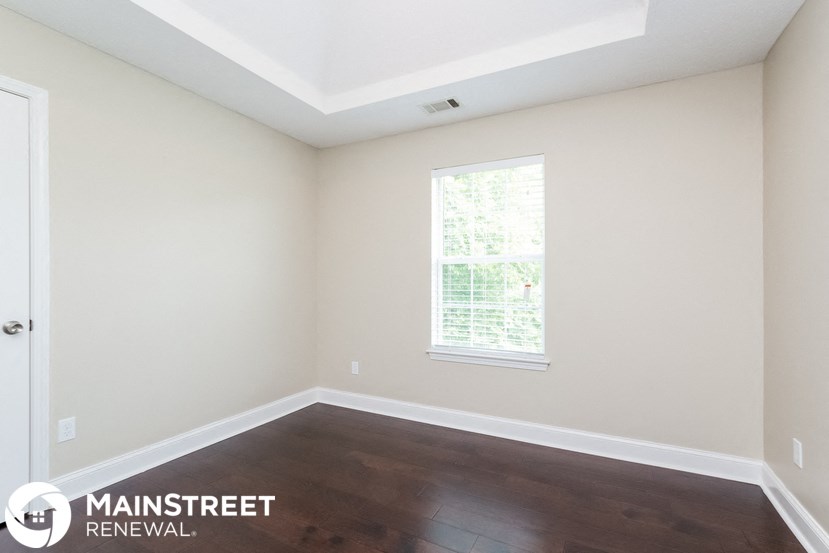 an empty room with wooden floors and a window