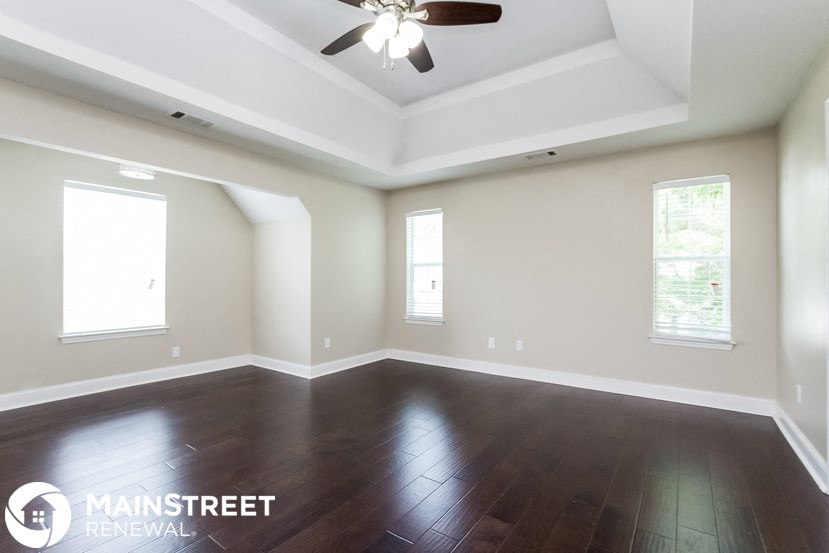 an empty living room with wood floors and a ceiling fan