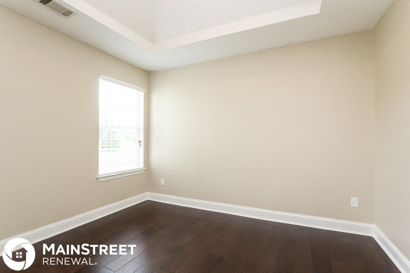 the living room of a home with wood flooring and a window
