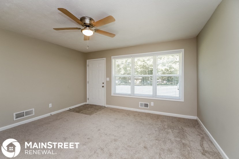 an empty bedroom with a ceiling fan and a window