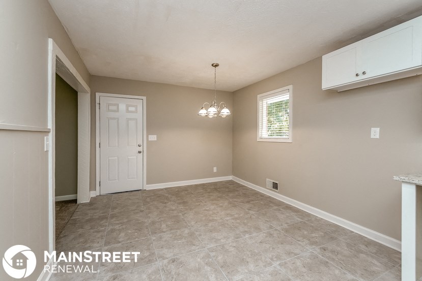 the living room of a home with a tile floor and a white door