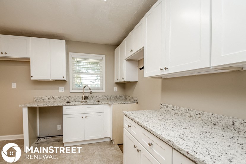 a white kitchen with marble counter tops and white cabinets