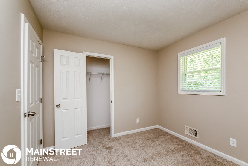 a bedroom with a closet and a white door and a window