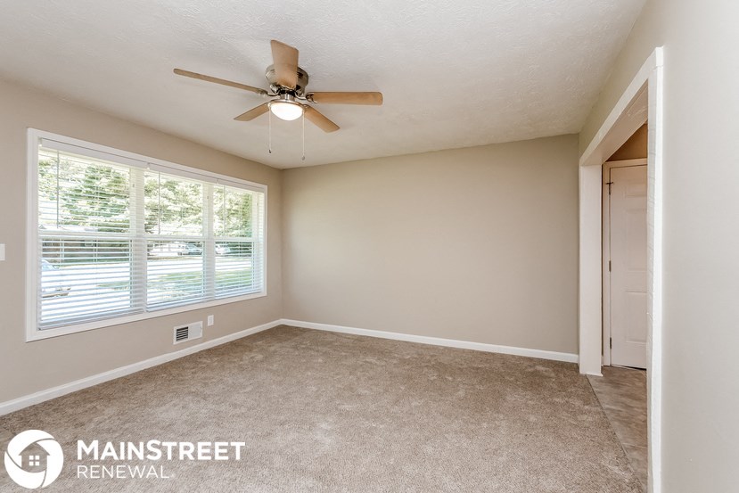 the master bedroom has a ceiling fan and a large window