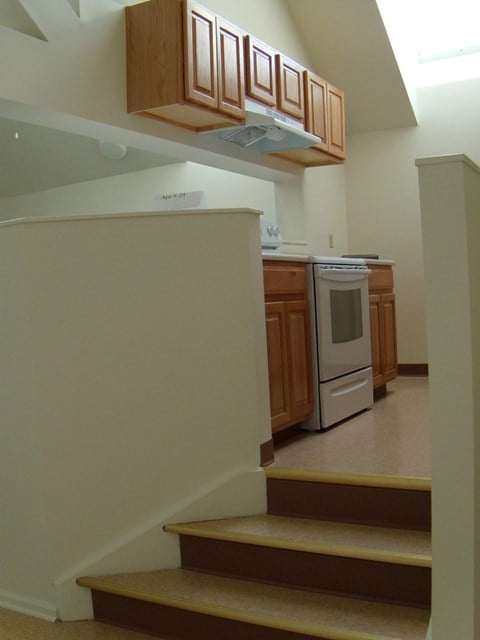 a view of a kitchen from the bottom of the stairs