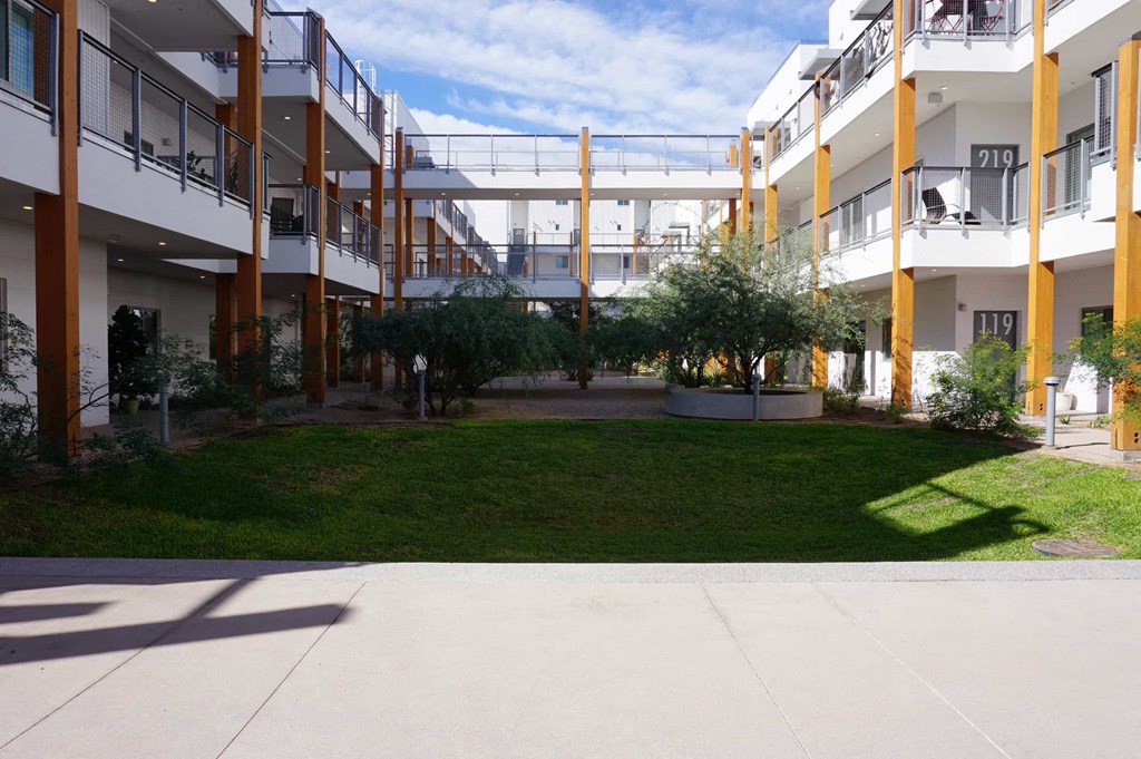 the courtyard of an apartment building with grass and trees