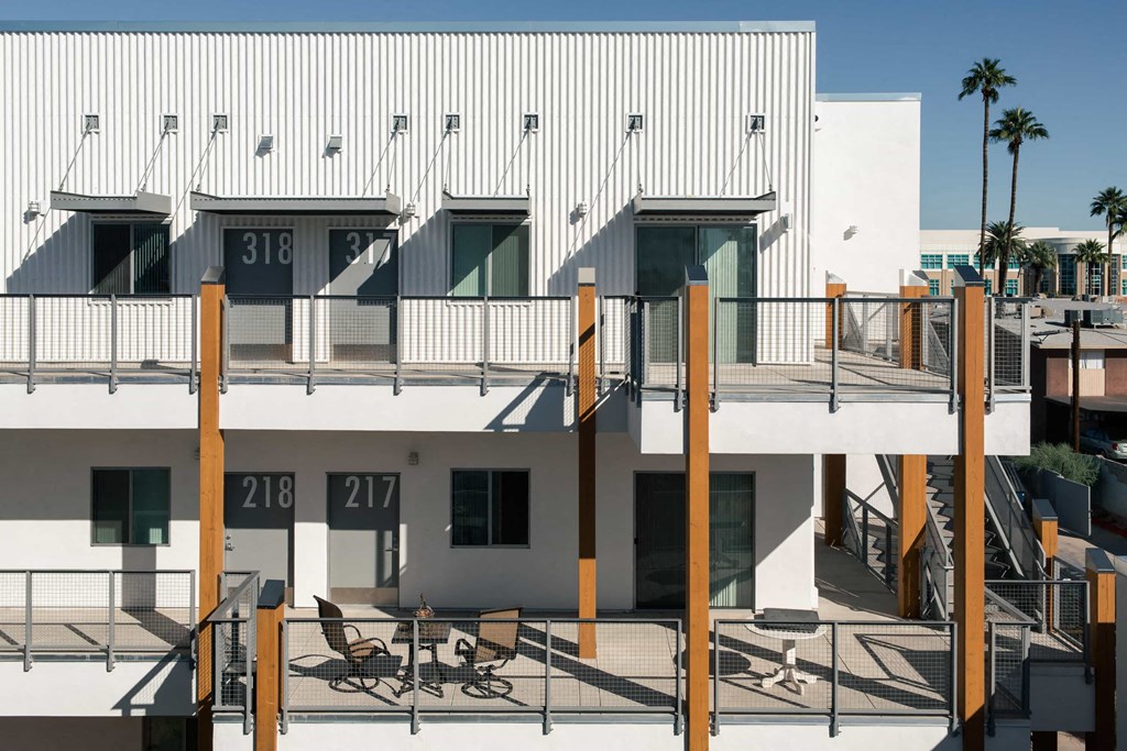 a view of a white building with balconies and a deck with chairs