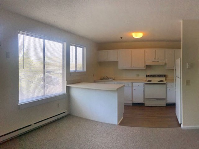an empty kitchen with white cabinets and a large window